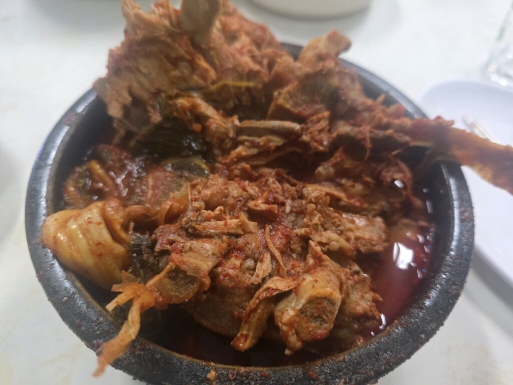 A close-up view of the massive pork spine bones heaping in a stone bowl, defining it as the most Dangerous Midnight Food in Korea.