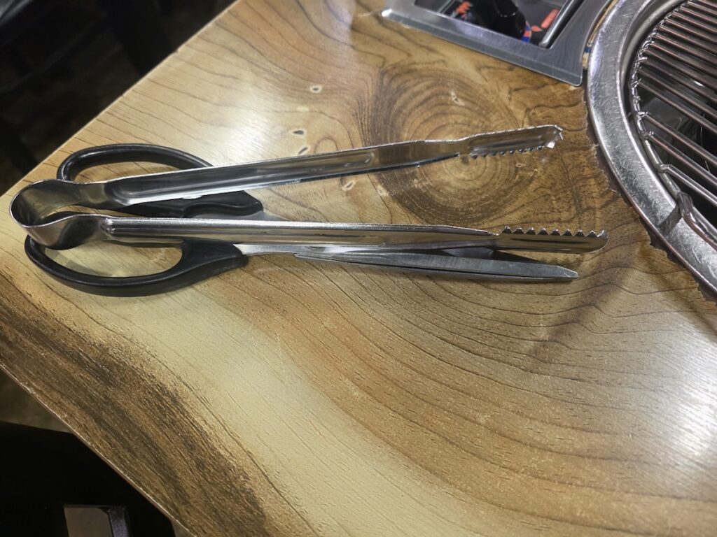 Scissors and metal tongs used at a Korean barbecue restaurant