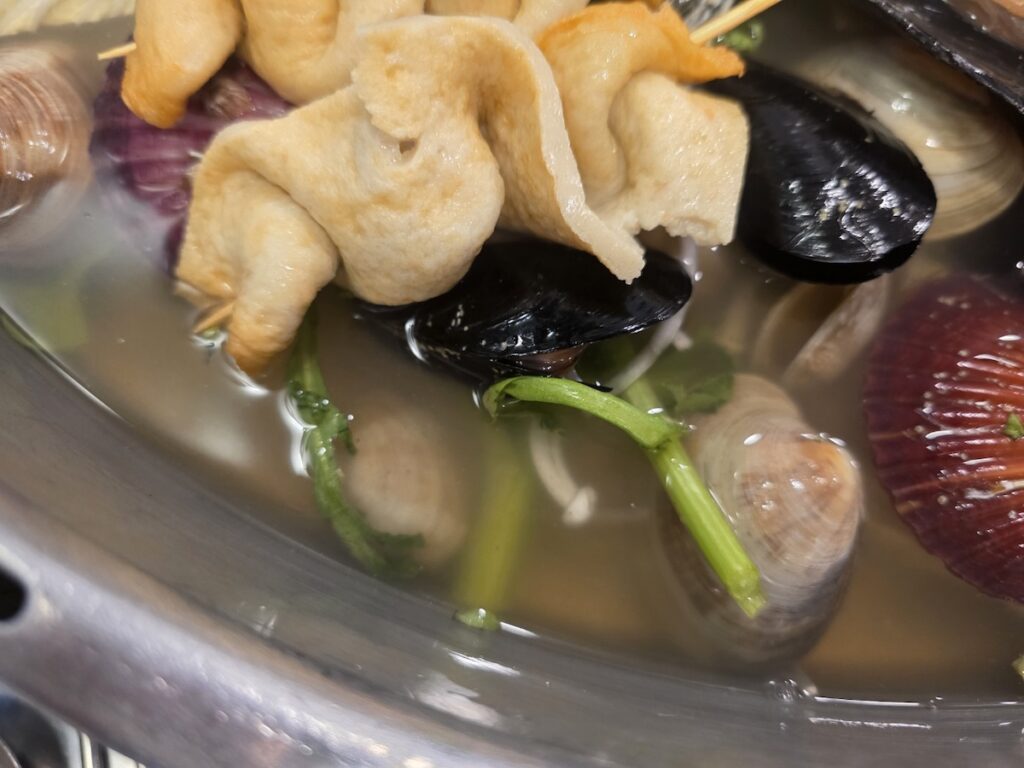 Close-up of skewered fish cakes and clams in the mineral-rich broth of the 3 Best Korean Steamed Seafood Rituals for Healthier Living.