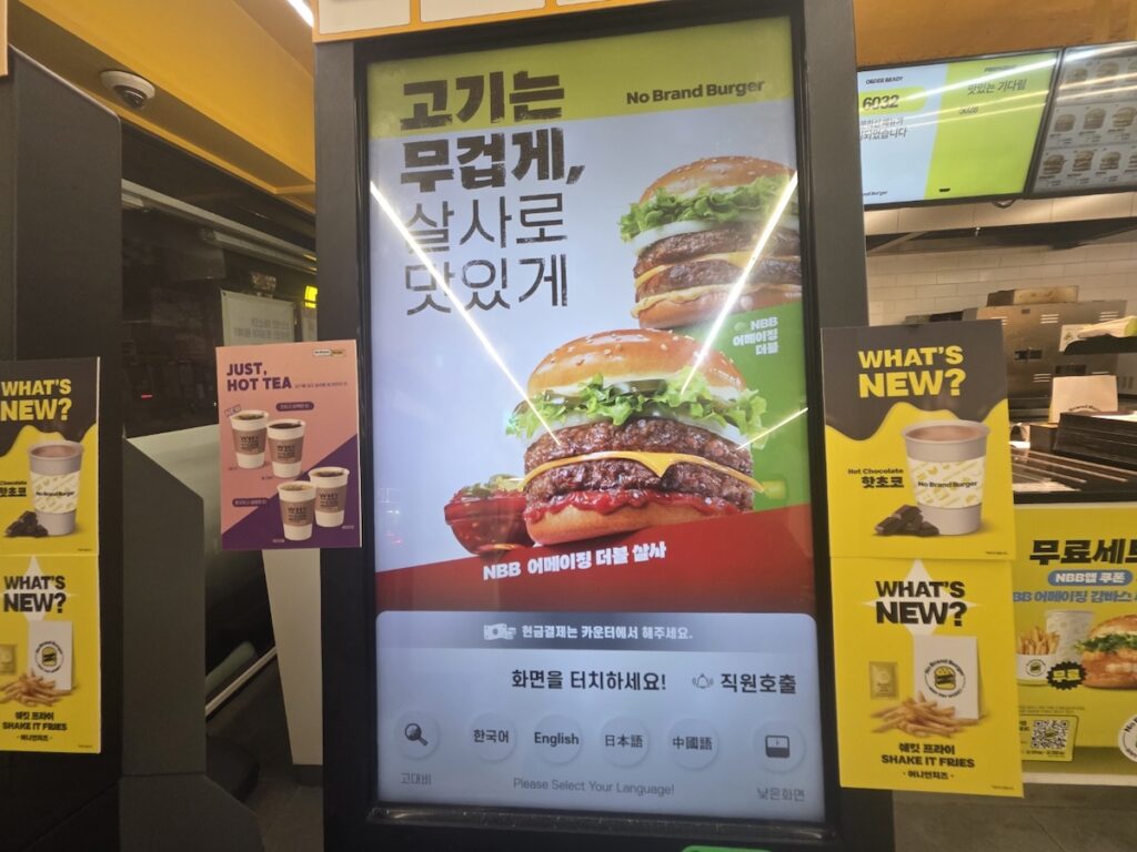 A digital kiosk at No Brand Burger showing language options for Korean, English, Japanese, and Chinese, making it an essential Seoul Gourmet Guide 2026 tip.