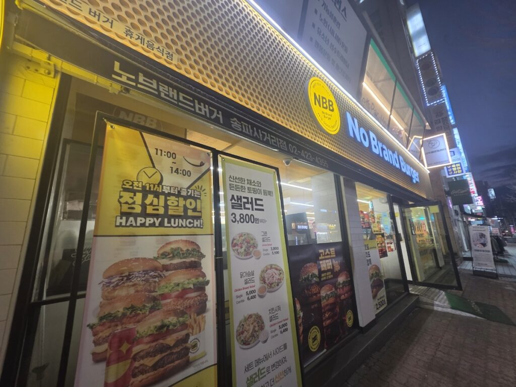 The bright yellow and black exterior of the NBB Songpa branch at night, a landmark for anyone seeking Korean Street Food Rituals in Seoul.