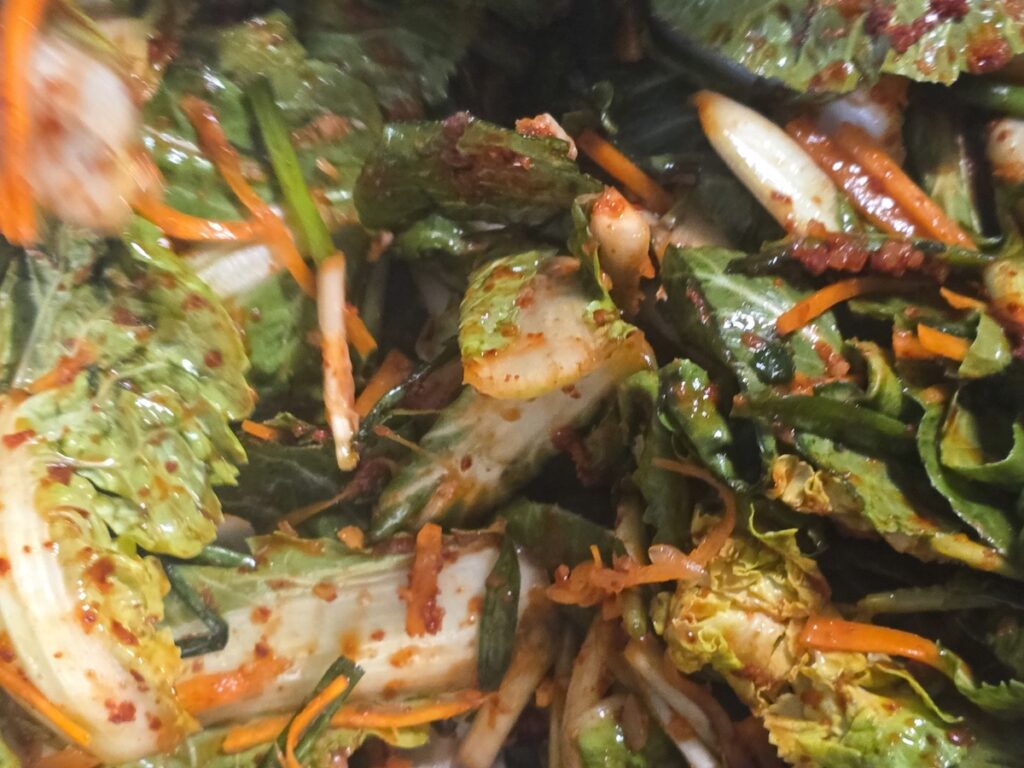 A close-up of the vibrant red seasoning on spring cabbage in the **Bomdong Geotjeori Ritual 2026**.