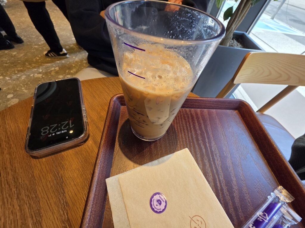 A close-up shot of the signature pebble ice and hazelnut beverage at Coffee Bean Korea with a smartphone on the table.