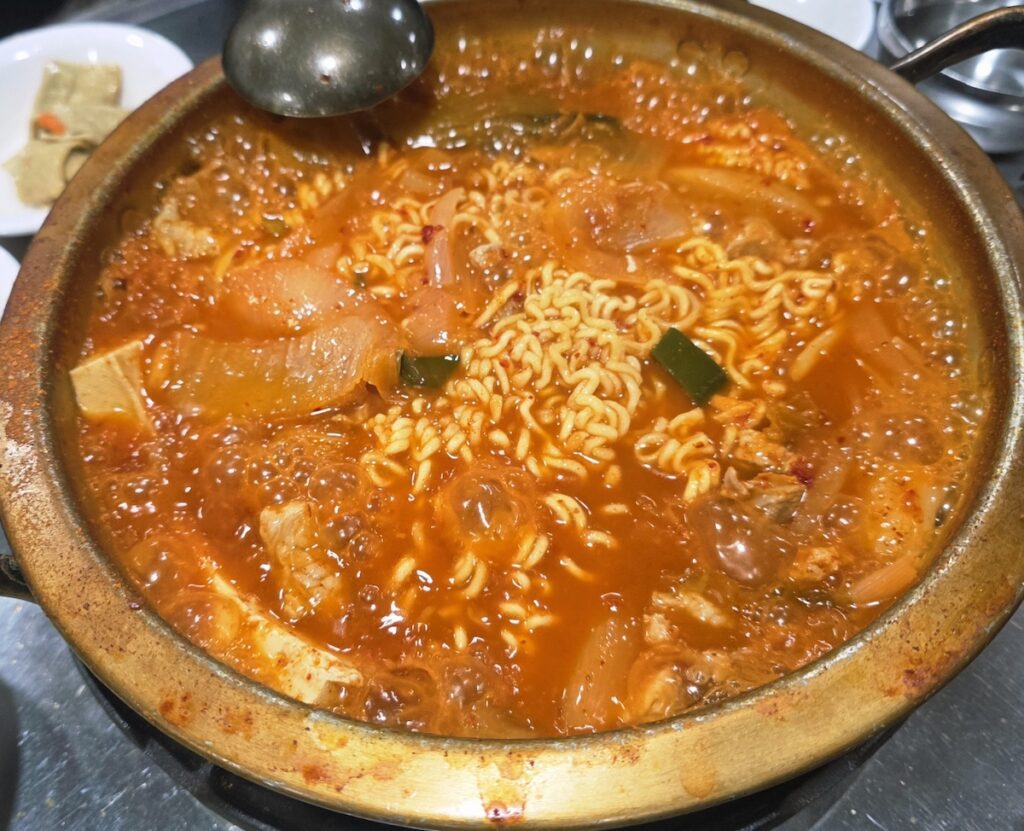 The complete **Gangnam Lunch Ritual** set at an affordable eatery in Seoul, featuring a spicy Kimchi-jjigae stew and black rice for only $6.00.