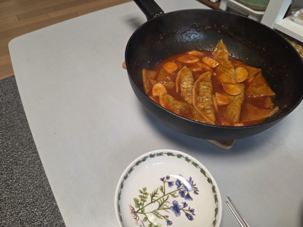 A pan of homemade Tteokbokki with mandu and fish cakes, illustrating the authentic Homemade Tteokbokki Ritual 2026.