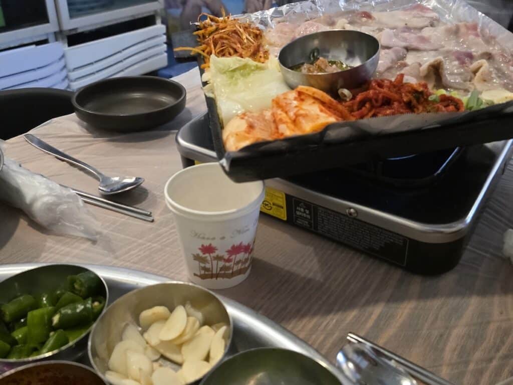 A paper cup placed under a slanted griddle to collect rendered pork fat, a unique K-BBQ ritual in Seoul.