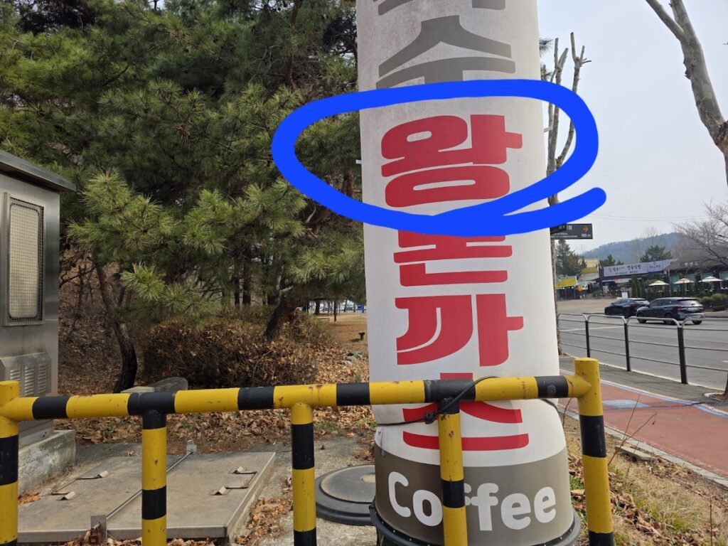 A signboard in Paju Heyri Art Valley, with the Korean character "Wang" (meaning King or Massive) circled in blue, advertising the famous King-sized Donkatsu of the region.