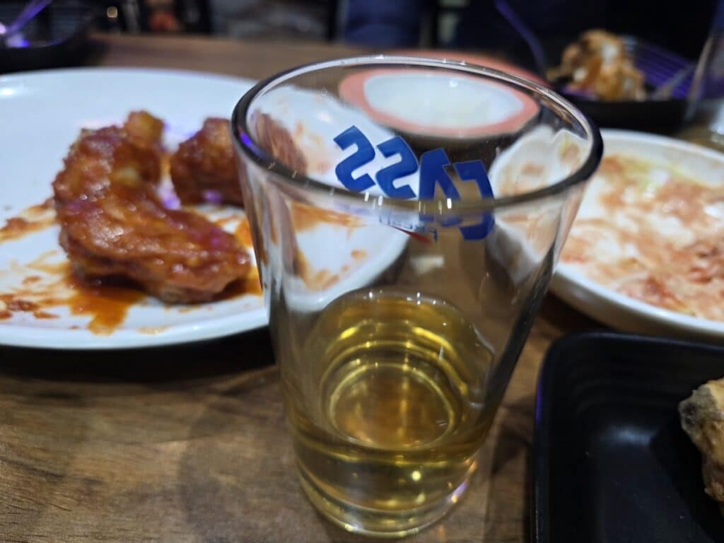 The Korea Beer Dilemma: A glass of golden beer is placed next to a plate of spicy Korean Yangnyeom chicken, capturing the heart of the Chimaek ritual.