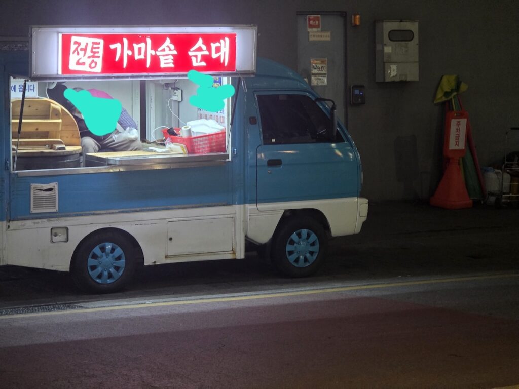 A blue food truck parked on a night street in Korea, selling traditional Gamasot Soondae as part of the Korea Street Food Guide 2026 ritual.