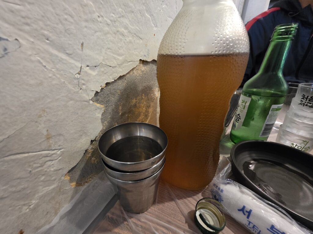 A nostalgic Del Monte glass bottle filled with amber-colored roasted barley tea, featuring cold condensation and a textured grip, symbolizing Korean Barley Tea Culture 2026.