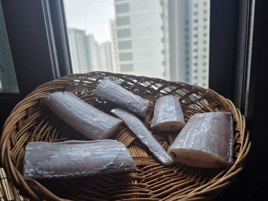 Korean Belt Fish Ritual: Preparing dried fish on a wicker basket, illustrating the cultural difference of Metal Chopsticks vs. Silverware in an authentic Seoul home.