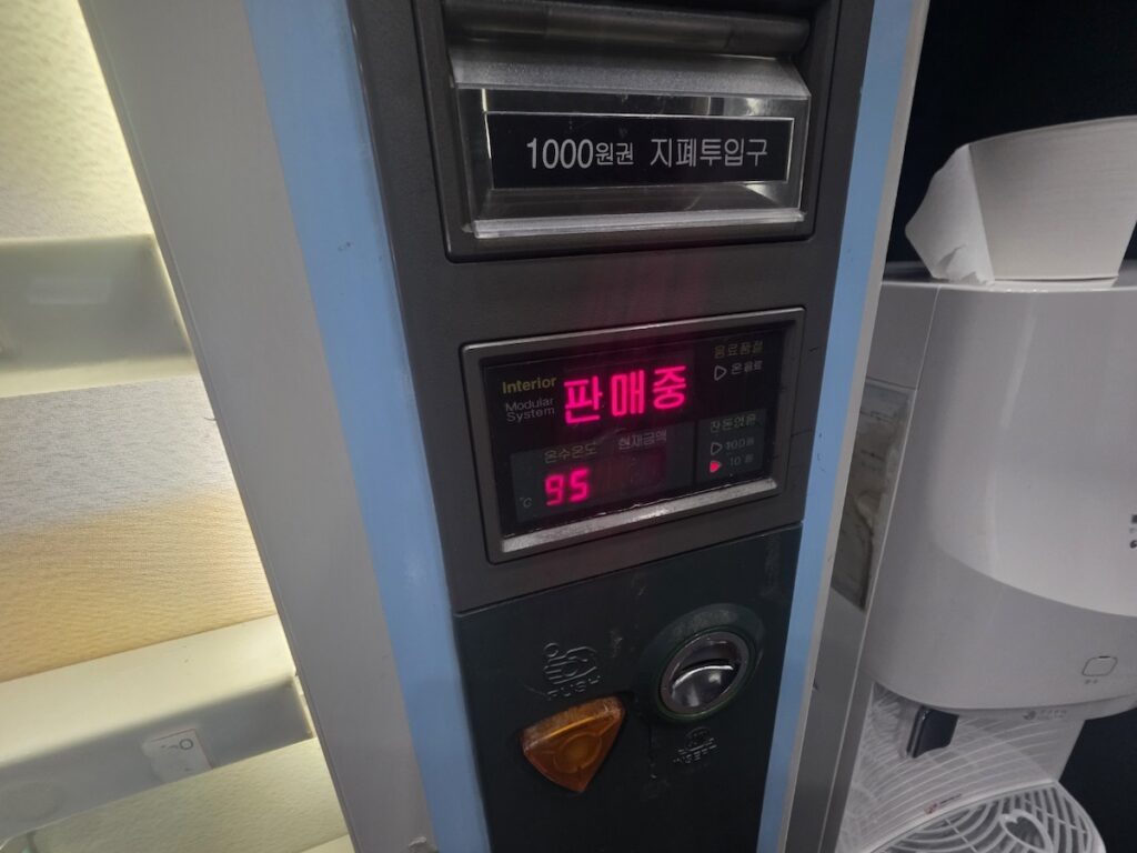 A digital display on a Korean coffee vending machine showing 95 degrees Celsius and a 1,000 won bill slot.