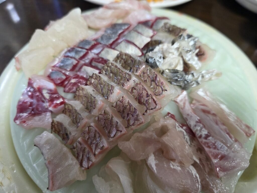 Korean Raw Fish Ssam Ritual: A platter of diverse Korean Hwe (raw fish) slices, featuring both soft flesh and textured skin-on pieces (like Rockfish or Sea Bream), prepared for the custom ssam experience.