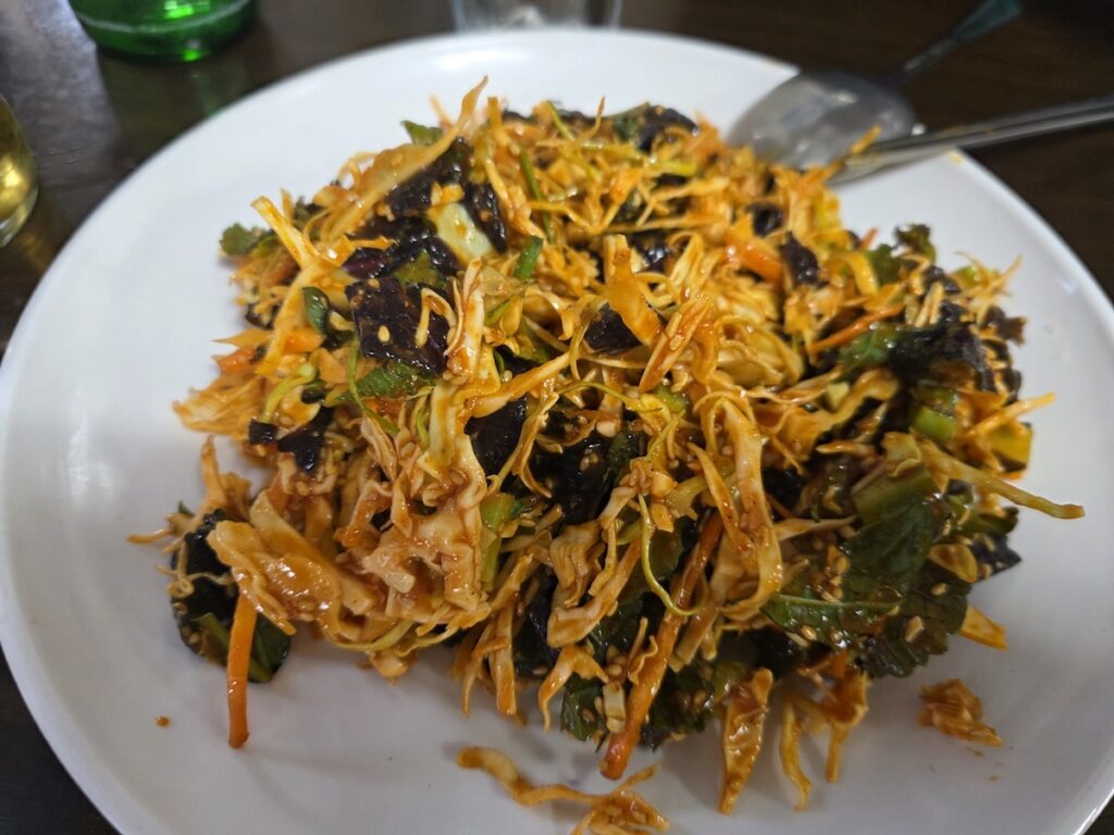 Korean Raw Fish Ssam Ritual: A large platter of seasoned shredded cabbage and perilla leaves mixed with a sweet and spicy dressing, providing a refreshing fiber buffer for the raw fish.