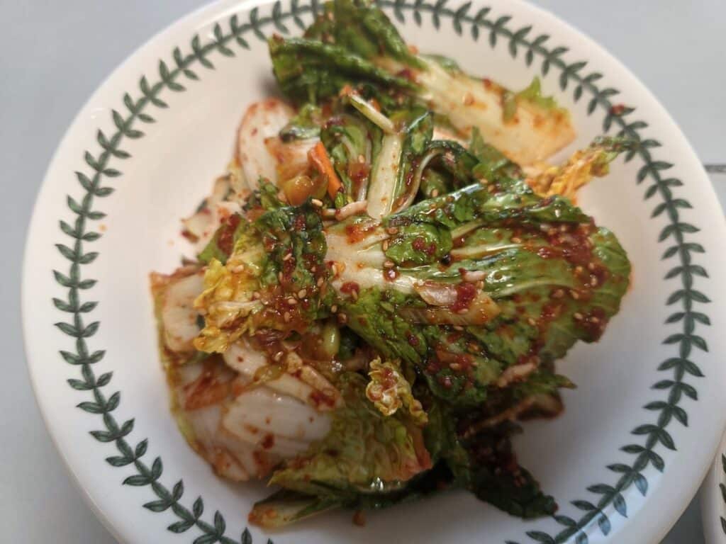 Vibrant and fresh Korean spring cabbage salad (Bom-dong Geot-jeori) tossed in spicy red pepper flakes, representing the seasonal freshness of Korean Banchan Diet Rituals.