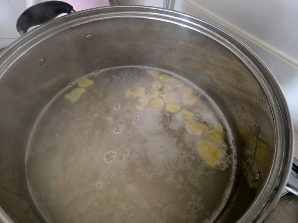 Best Korean Desserts: A wide shot of a stainless steel pot on a gas range, with a faint steam rising from the simmering, pale Sikhye liquid, emphasizing the traditional slow-boiling method.