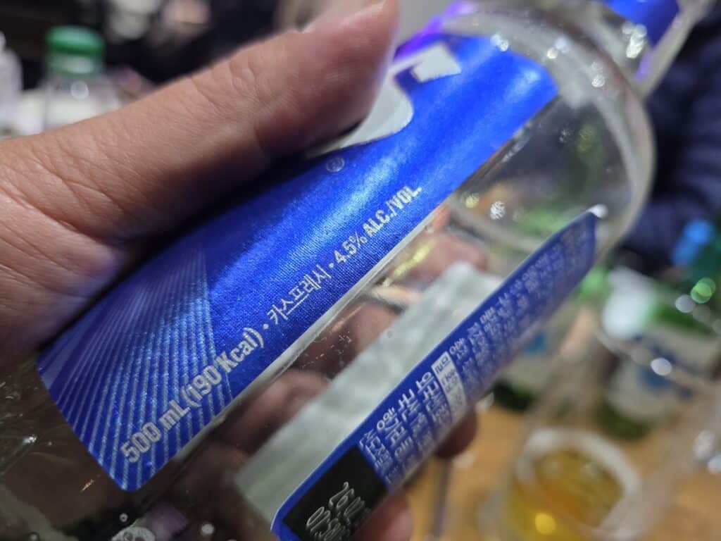 A detailed close-up of a 500ml bottled beer label held in hand, representing the 'Sensible Drinker's' choice for consistent flavor over draft variables.