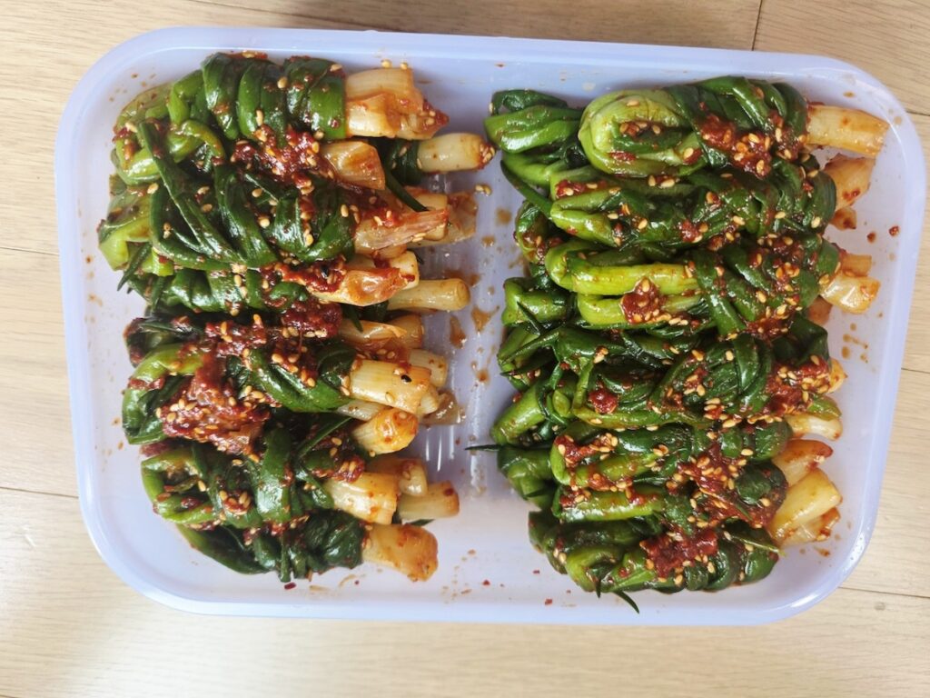 The Most Delicious Kimchi featuring the "Twirl Technique," where green onions are meticulously bundled into bite-sized rolls, representing the sophisticated evolution of Vegan Kimchi Seoul.