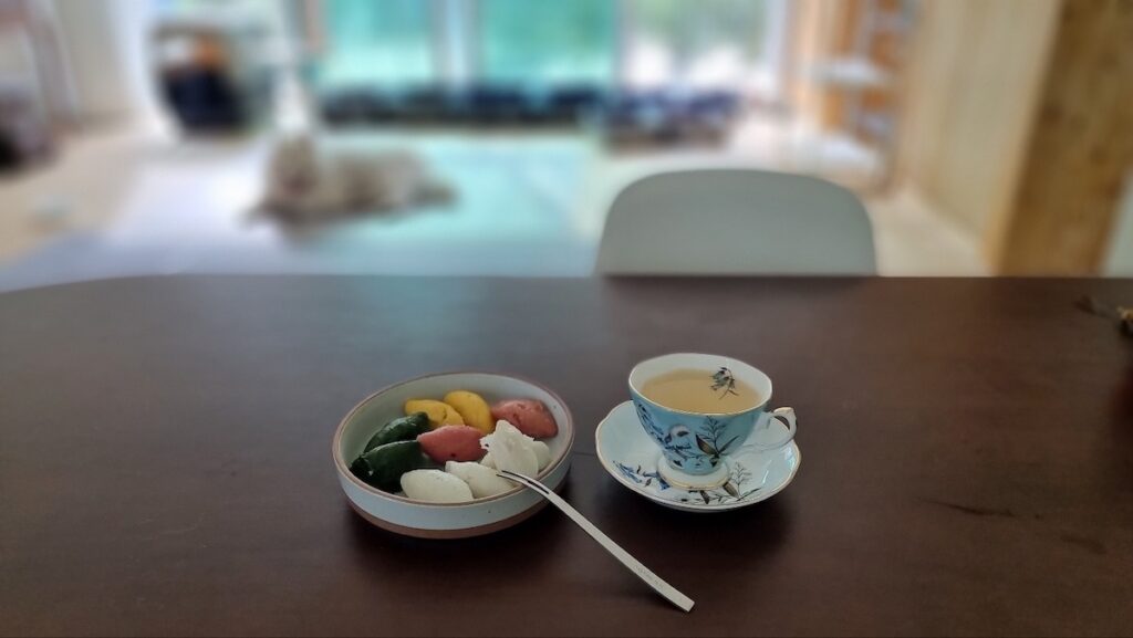 A sophisticated afternoon tea setting featuring colorful rice cakes and a Royal Albert cup, embodying the serene Traditional Korean Rice Cake Pairing 2026.