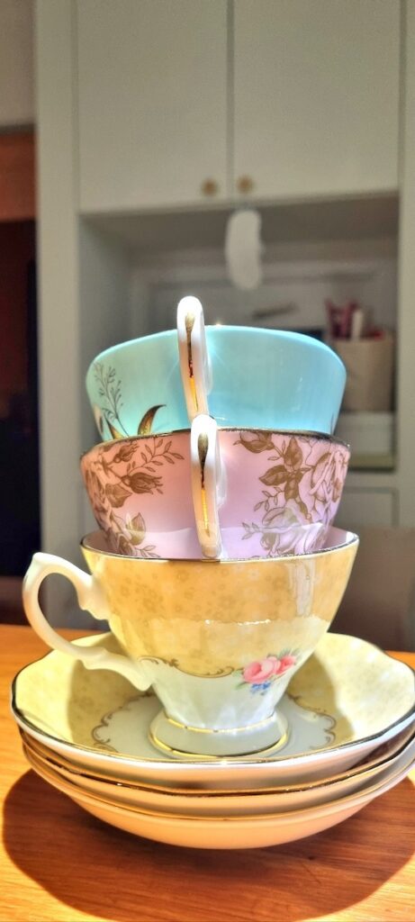 A cinematic stack of Royal Albert Miranda Kerr teacups in turquoise, pink, and yellow, representing the luxury elements of Traditional Korean Rice Cake Pairing 2026.