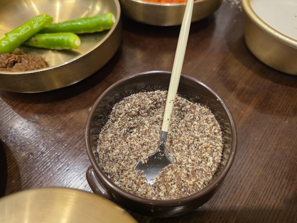 A small bowl of crushed perilla seeds (Deulggae-garu), used to add a nutty depth to the Authentic Korean Hangover Soup.