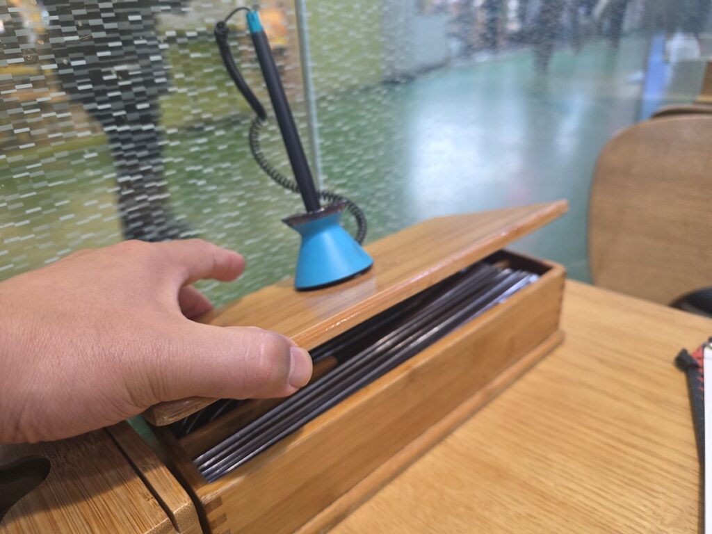 A view of a cluttered terminal restaurant order sheet, focusing on the "Anju" (snacks with alcohol) section where dishes like Jeyuk-bokkeum are priced at an exorbitant 35,000 KRW, illustrating a tourist scam.