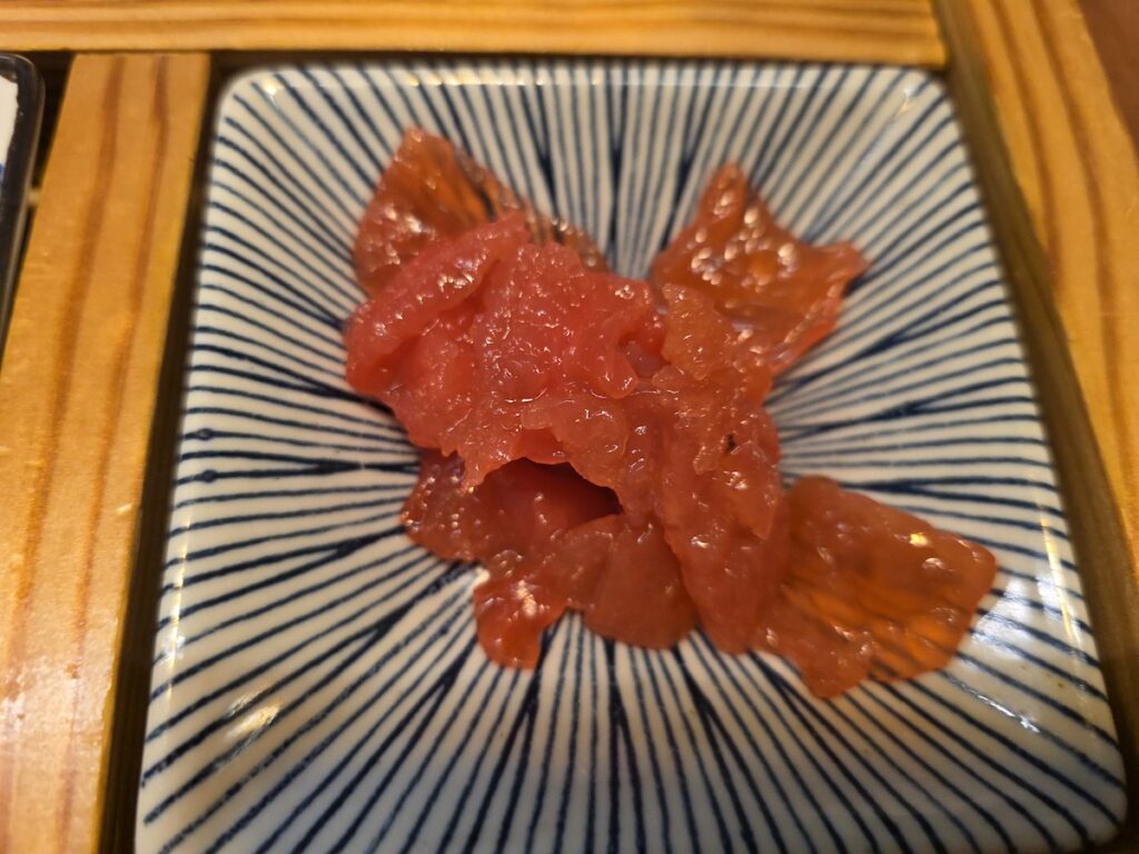 A close-up of shredded seaweed (Sea Mustard) mixed with seasoning, a typical healthy and diet-friendly side dish in a Korean sashimi restaurant.