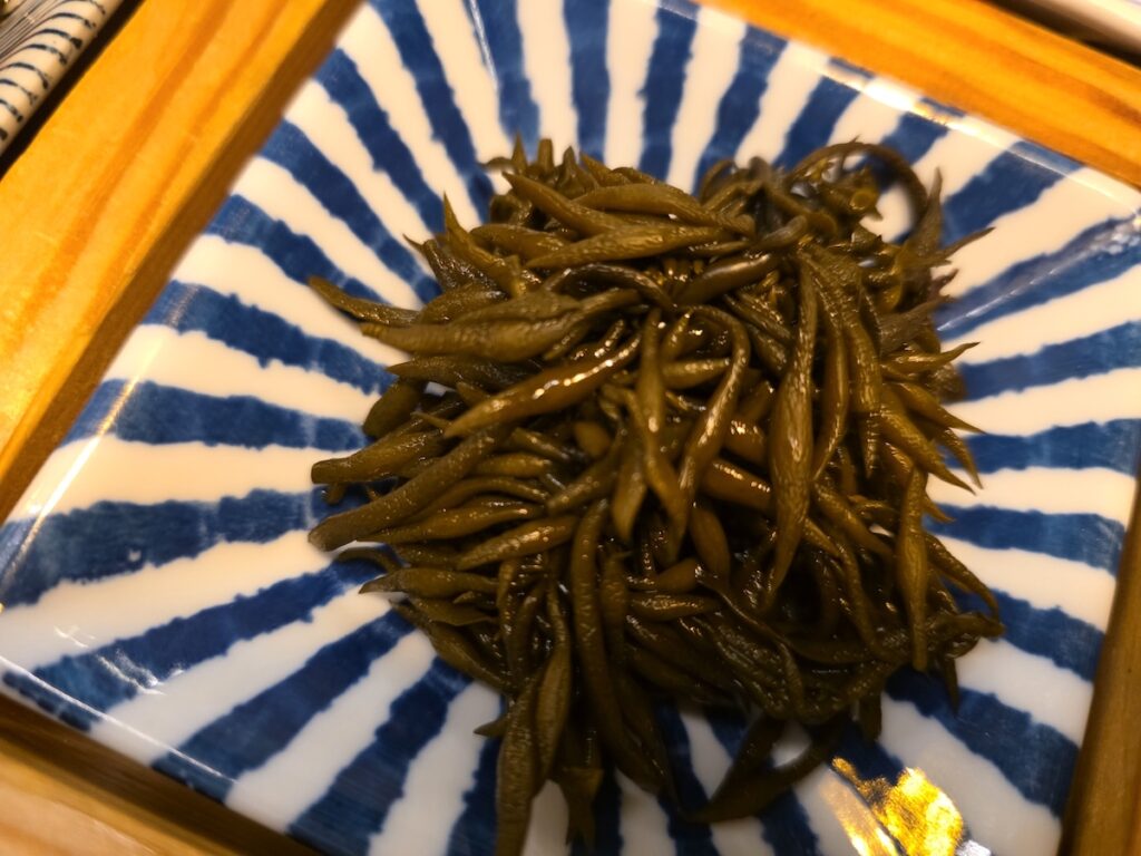 A close-up of fresh, dark brown Sargassum (Tot) seaweed, served as a nutrient-rich and fiber-packed side dish in a Korean seafood restaurant for weight-loss.