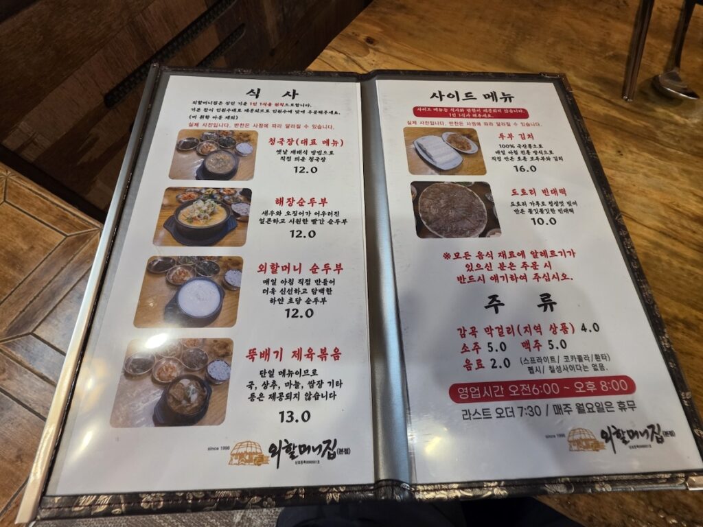 A photo of a restaurant menu for a what is why how guide explained, showing Cheonggukjang priced at 12,000 KRW and other traditional dishes like Sundubu and Jeyuk-bokkeum.