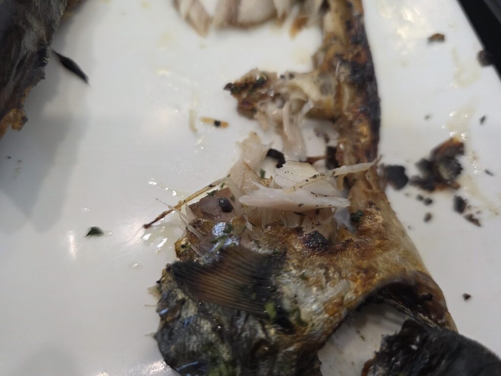 Close-up of Korean grilled fish bones left on a white plate after eating mackerel, showing how difficult Korean grilled fish bones can be for first-time visitors