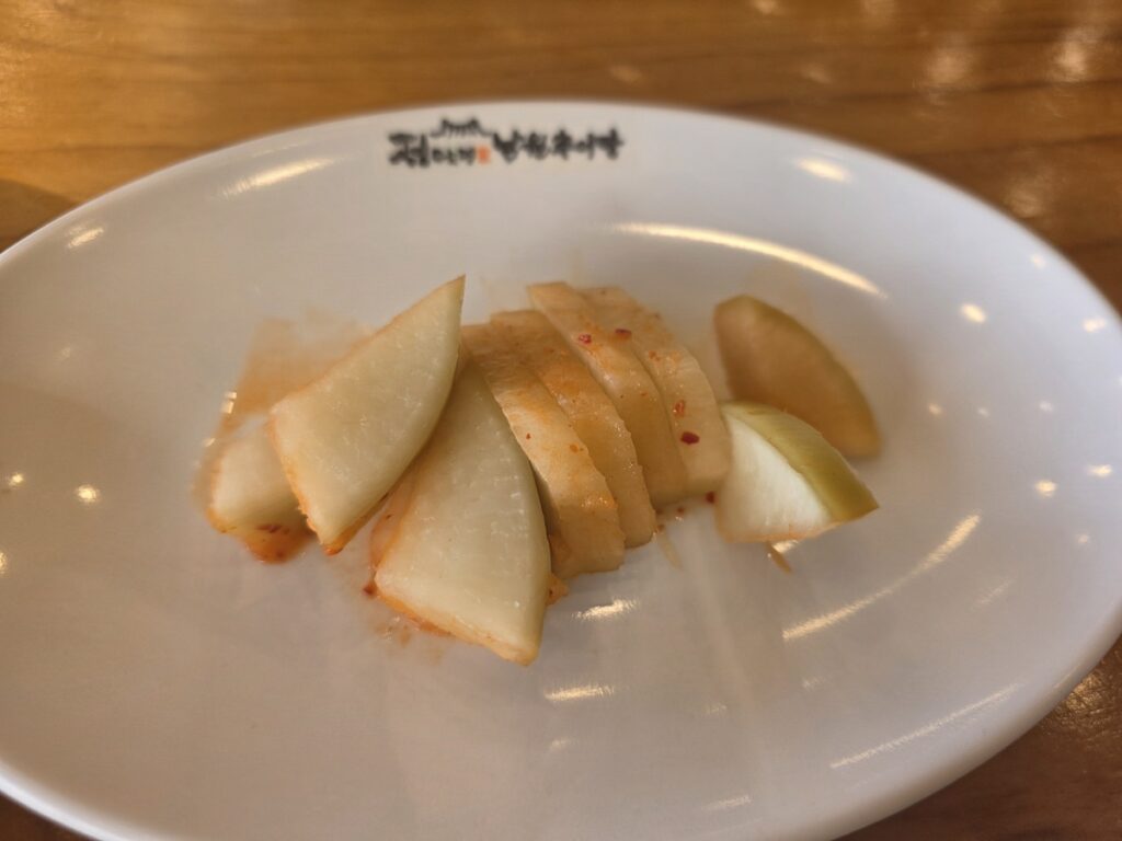 Sliced pieces of crunchy fermented radish kimchi, or kkakdugi, served on a white plate in a Seoul restaurant.
