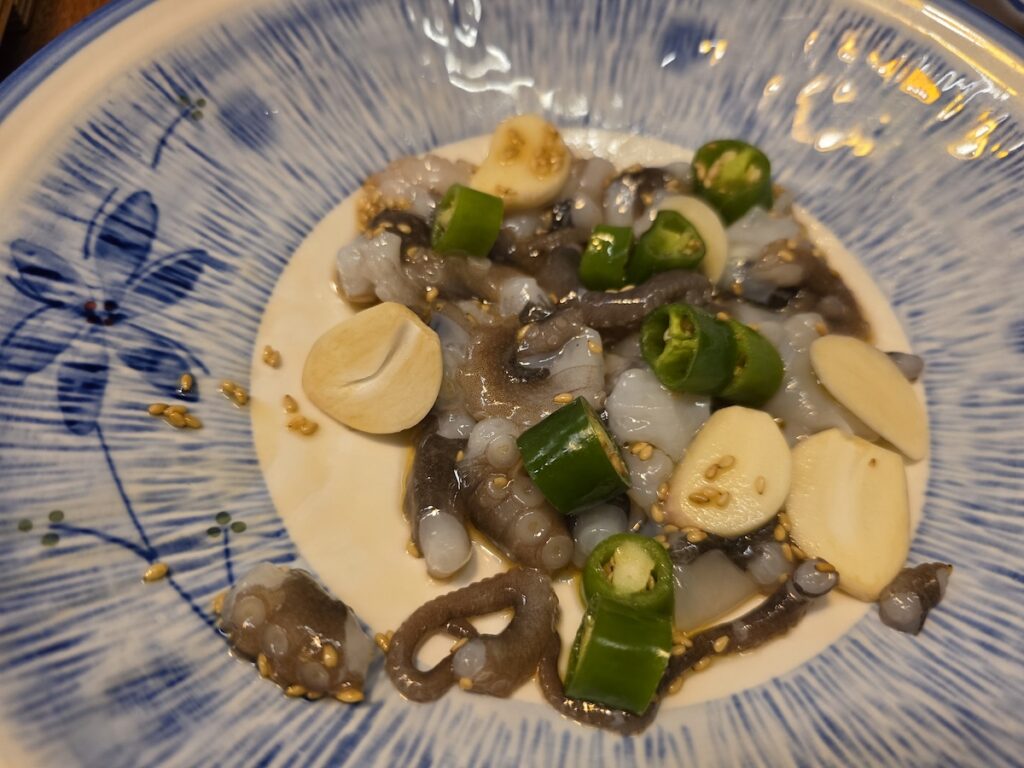 A plate of sannakji, or squirming live octopus tentacles, seasoned with sesame seeds, garlic, and green chili peppers.