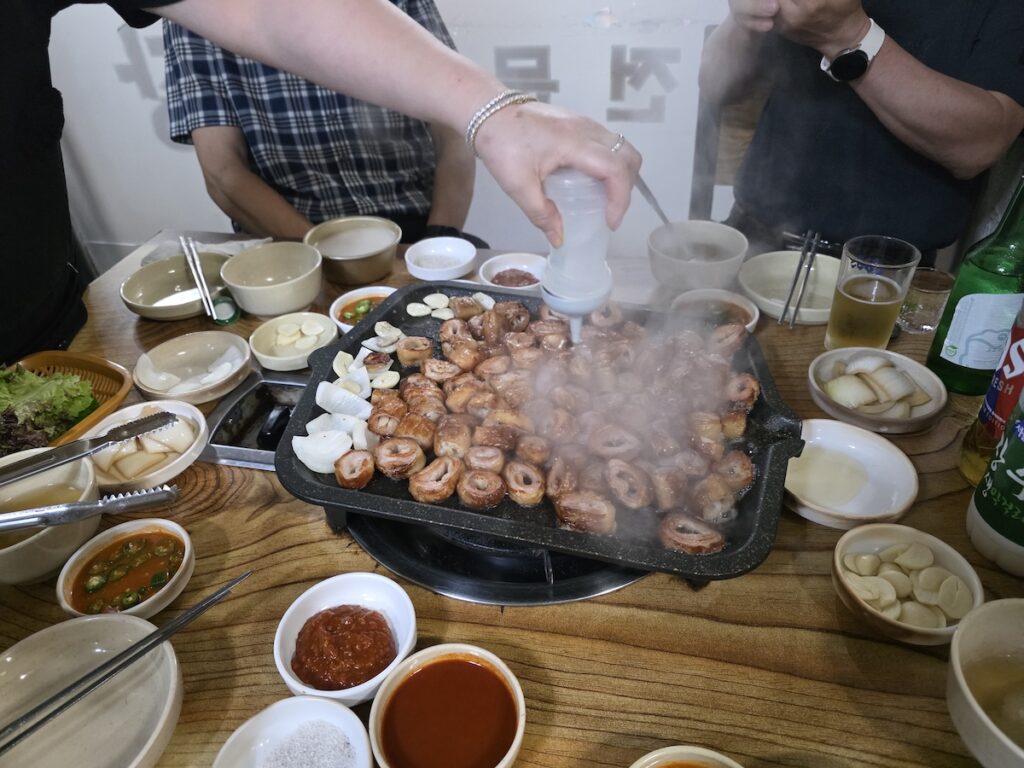 A bustling restaurant table with grilled makchang and various dipping sauces.