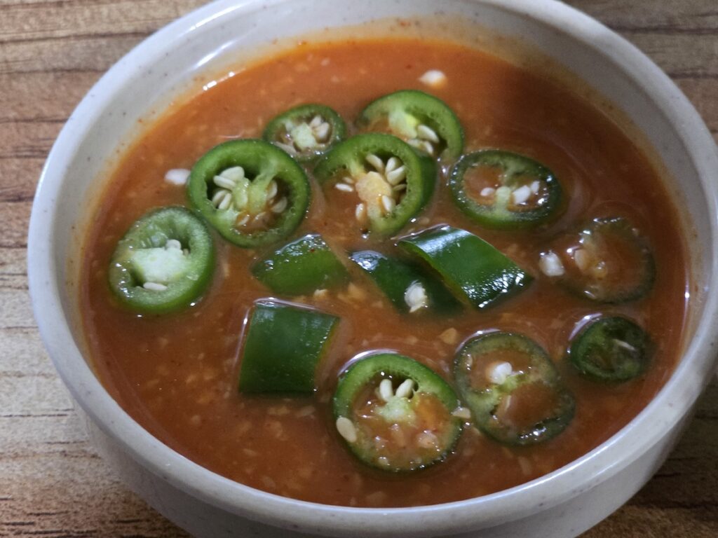 A small bowl of Korean ssamjang topped with fresh green chili slices.