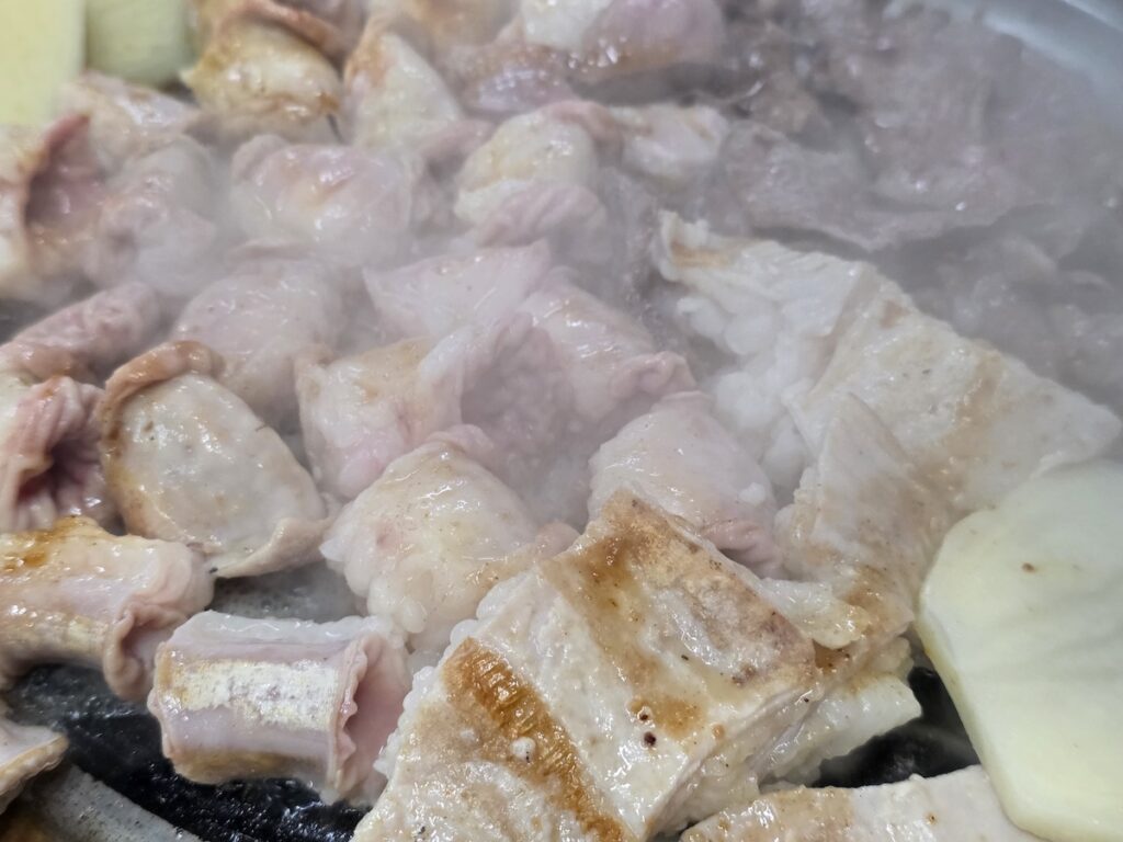 Close-up of Korean beef intestines gopchang and daechang pieces cooking with steam rising